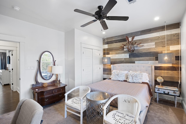 bedroom with wooden walls, a closet, and ceiling fan