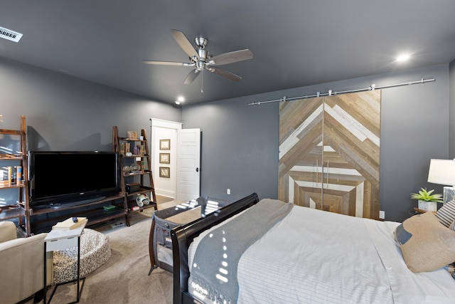 bedroom with carpet floors, a barn door, and ceiling fan