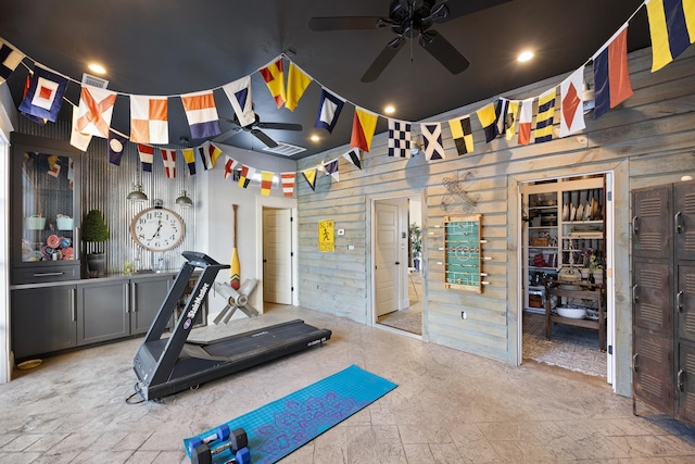 workout room featuring ceiling fan and wood walls