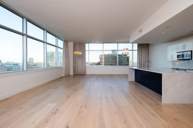 unfurnished living room with sink and light wood-type flooring