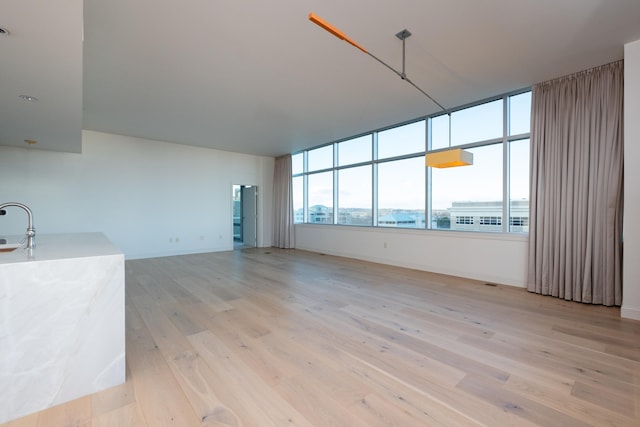 unfurnished living room with sink and light hardwood / wood-style floors