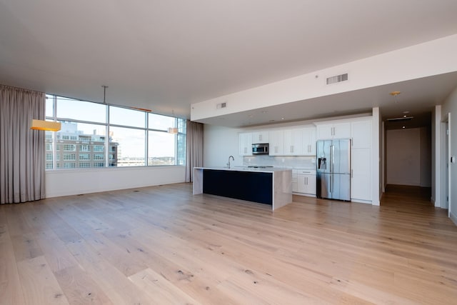 kitchen featuring a kitchen island with sink, light hardwood / wood-style flooring, white cabinets, and appliances with stainless steel finishes