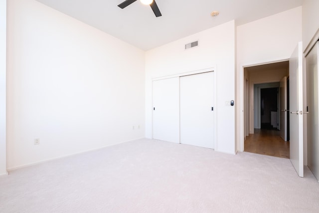 unfurnished bedroom with light colored carpet, a closet, and ceiling fan