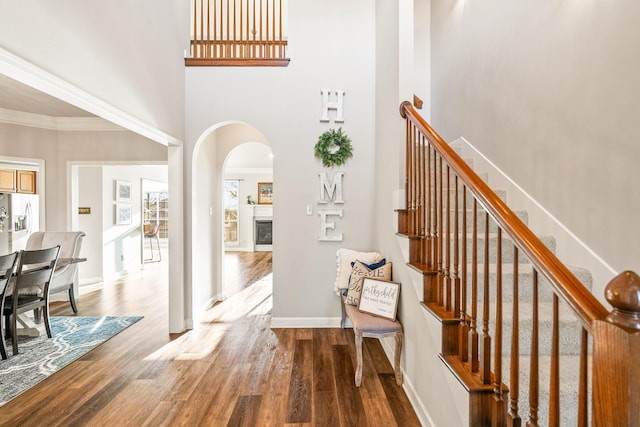 interior space featuring ornamental molding, wood-type flooring, and a towering ceiling