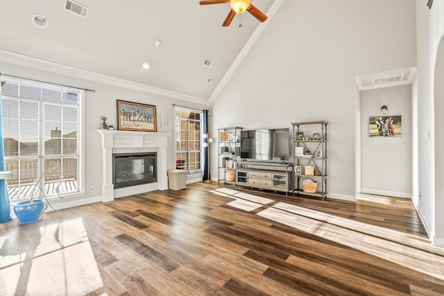 unfurnished living room featuring hardwood / wood-style floors, crown molding, high vaulted ceiling, and a healthy amount of sunlight