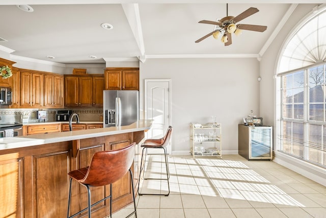 kitchen featuring light tile patterned floors, decorative backsplash, stainless steel appliances, and a kitchen bar