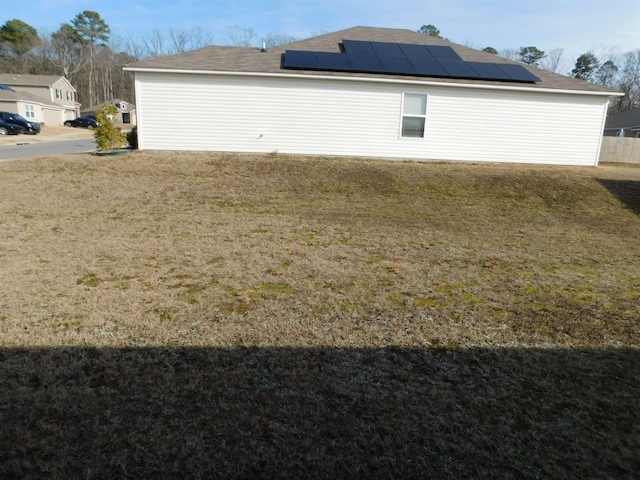 view of side of property featuring a lawn and solar panels