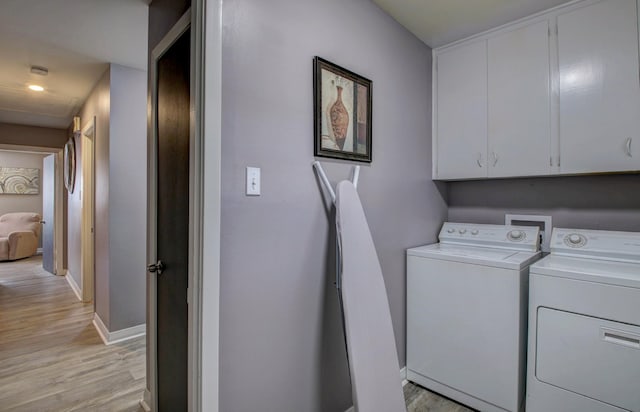 laundry room featuring cabinets, washing machine and dryer, and light hardwood / wood-style floors