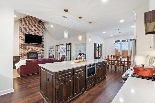 kitchen with stainless steel appliances, hanging light fixtures, a center island, and a barn door