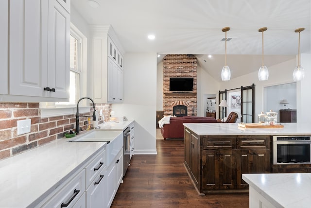 kitchen featuring sink, decorative light fixtures, appliances with stainless steel finishes, a barn door, and white cabinets