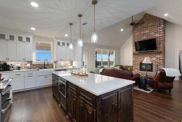 kitchen featuring sink, tasteful backsplash, white cabinetry, dark hardwood / wood-style flooring, and a kitchen island