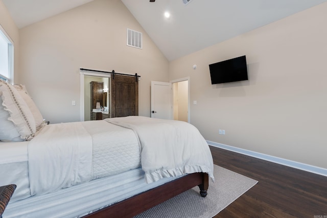 bedroom featuring dark hardwood / wood-style flooring, high vaulted ceiling, and a barn door
