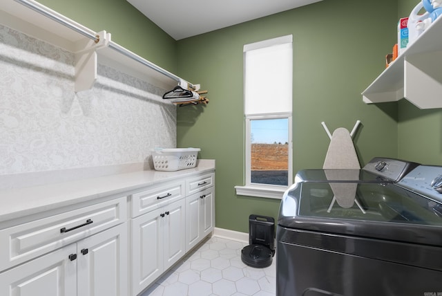 laundry room featuring cabinets, light tile patterned floors, and washing machine and clothes dryer