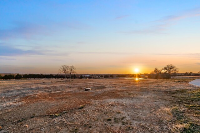 yard at dusk featuring a rural view