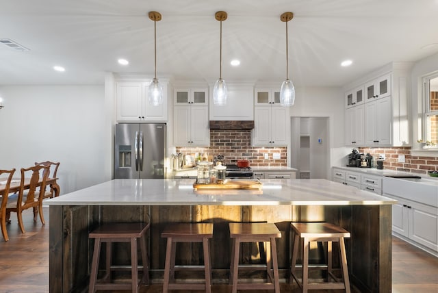 kitchen featuring backsplash, white cabinets, a spacious island, and appliances with stainless steel finishes