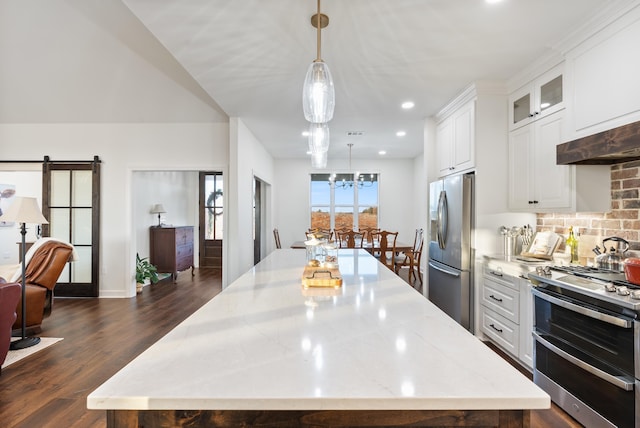 kitchen with appliances with stainless steel finishes, white cabinets, hanging light fixtures, light stone counters, and a barn door