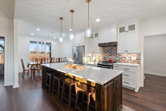 kitchen featuring stainless steel appliances, a center island, white cabinets, and decorative light fixtures