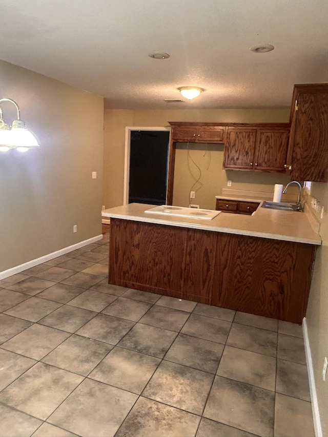 kitchen with tile patterned floors, kitchen peninsula, and sink