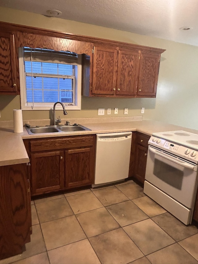 kitchen featuring light tile patterned flooring, white appliances, and sink