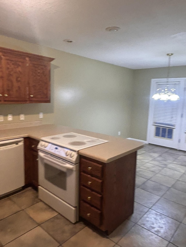 kitchen featuring kitchen peninsula, a notable chandelier, pendant lighting, white appliances, and tile patterned flooring