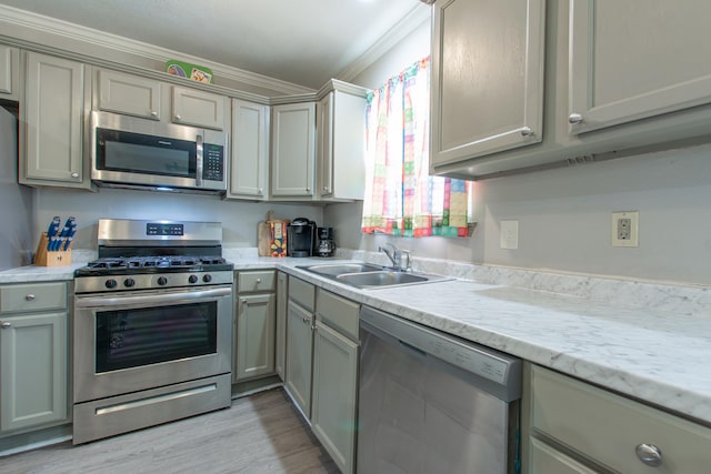 kitchen featuring appliances with stainless steel finishes, sink, gray cabinetry, light stone counters, and light hardwood / wood-style floors