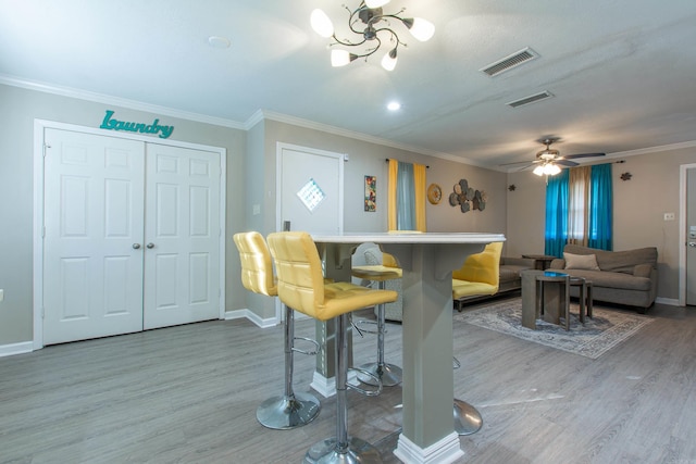 dining space featuring crown molding, bar, and light wood-type flooring