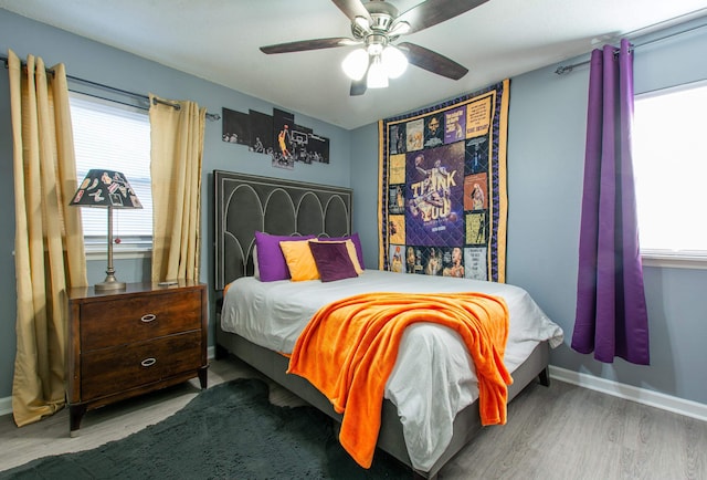 bedroom featuring hardwood / wood-style flooring, ceiling fan, and multiple windows