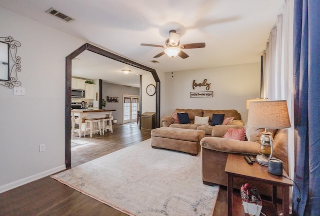 living room featuring dark wood-type flooring and ceiling fan