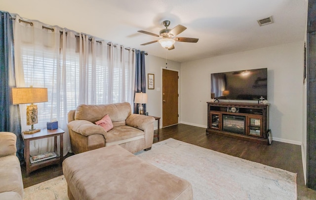 living room featuring dark wood-type flooring and ceiling fan