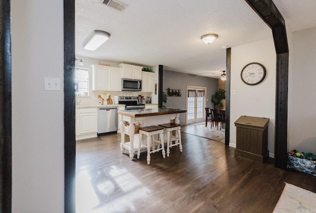 kitchen with white cabinetry, a healthy amount of sunlight, stainless steel appliances, and dark hardwood / wood-style floors