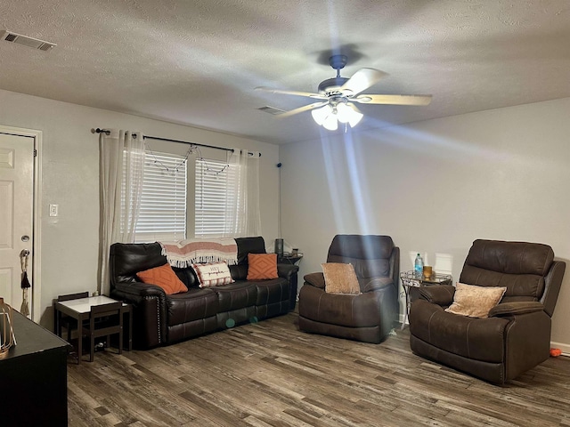 living room featuring ceiling fan, dark hardwood / wood-style floors, and a textured ceiling