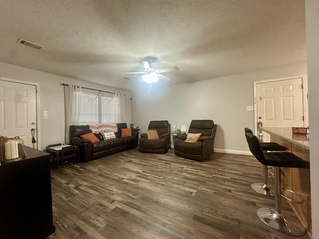 living room featuring ceiling fan, dark hardwood / wood-style floors, and a textured ceiling