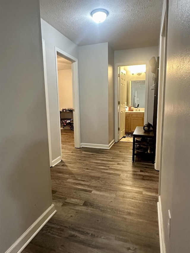 hall with dark wood-type flooring and a textured ceiling