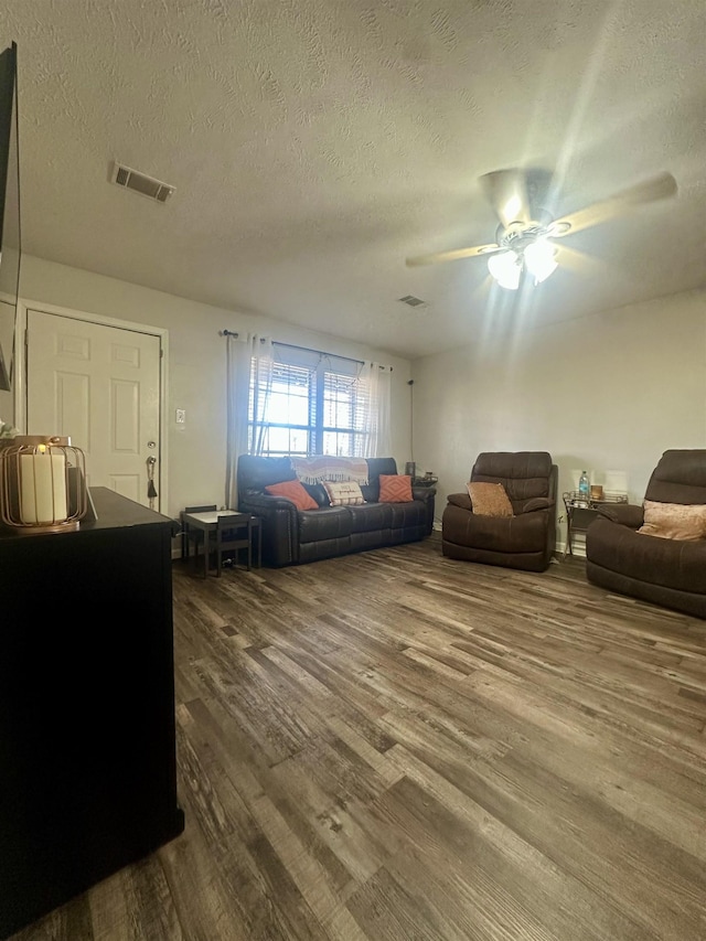 living room with ceiling fan, hardwood / wood-style flooring, and a textured ceiling