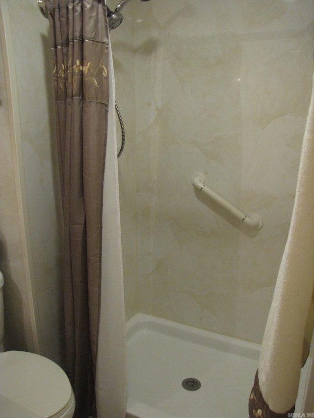 bathroom featuring a shower with curtain and toilet