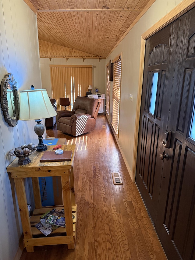 hallway featuring wood ceiling, wood-type flooring, wooden walls, and vaulted ceiling