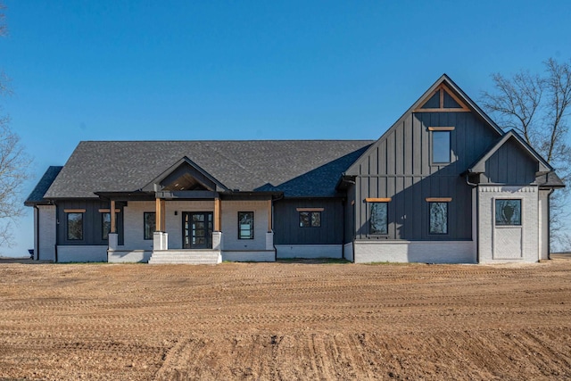 modern farmhouse style home with covered porch and a front lawn