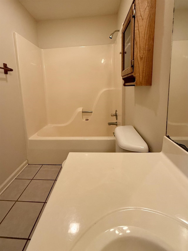 bathroom with tile patterned flooring, tub / shower combination, and toilet