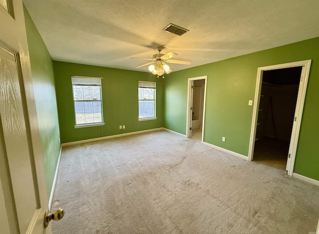 empty room with ceiling fan, light carpet, and a textured ceiling