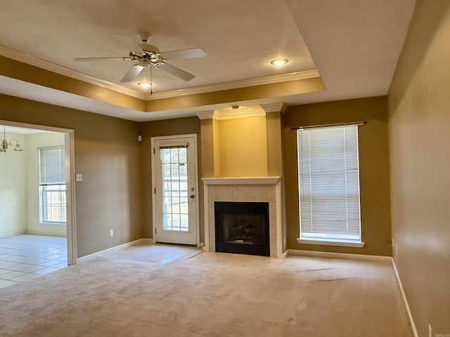 unfurnished living room featuring a tray ceiling, a tiled fireplace, and light carpet