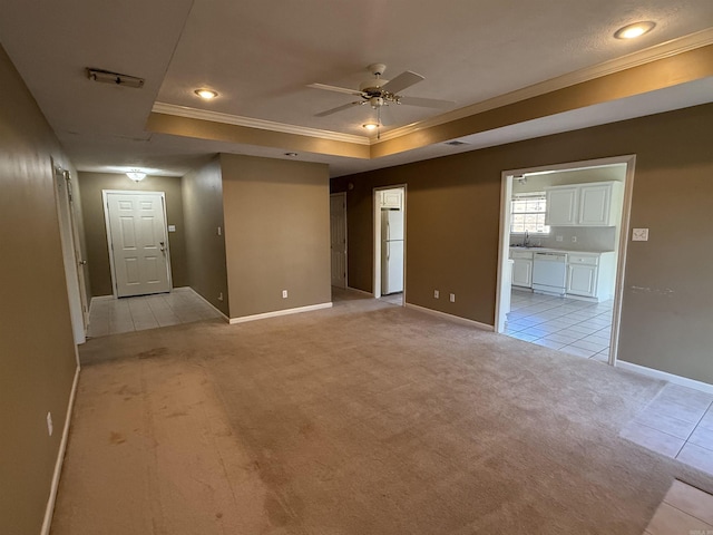 spare room with crown molding, light colored carpet, a tray ceiling, and ceiling fan