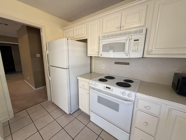 kitchen with white cabinetry, light tile patterned floors, and white appliances