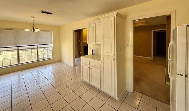 kitchen with light tile patterned floors, white cabinetry, decorative light fixtures, a chandelier, and white fridge