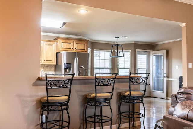 kitchen with decorative backsplash, a breakfast bar area, ornamental molding, and stainless steel refrigerator with ice dispenser