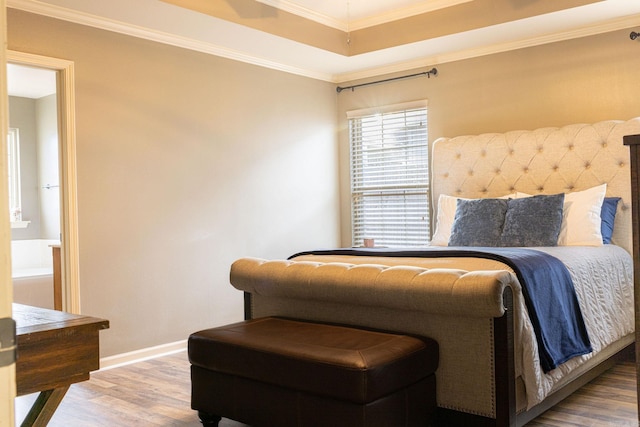 bedroom featuring hardwood / wood-style flooring, ornamental molding, and a raised ceiling