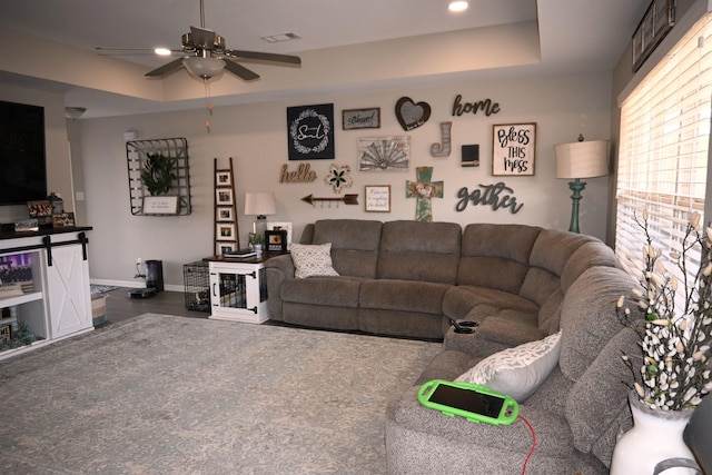 living room featuring a raised ceiling and ceiling fan