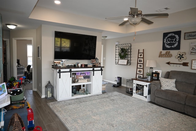 living room featuring a raised ceiling and ceiling fan