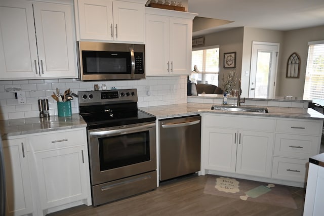 kitchen with tasteful backsplash, stainless steel appliances, sink, and white cabinets