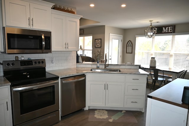 kitchen with sink, kitchen peninsula, white cabinets, and appliances with stainless steel finishes