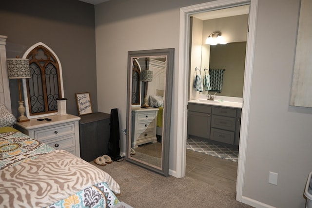 bedroom featuring ensuite bath, sink, and light colored carpet